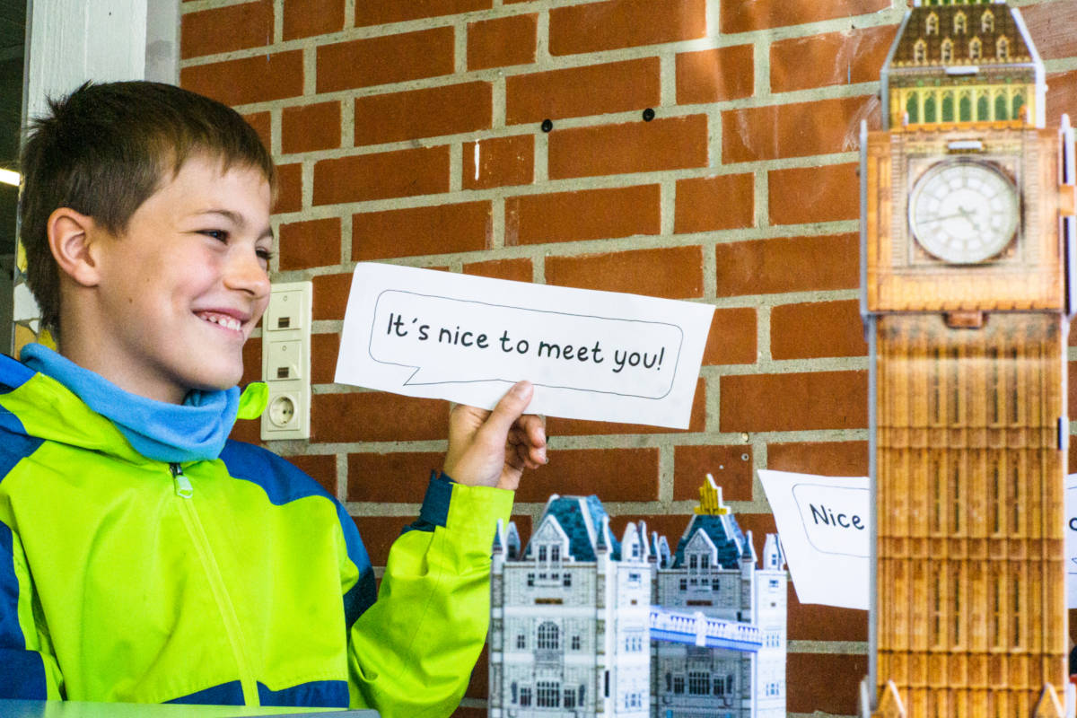 Ein Schüler steht neben einem Modell des Big Ben und hält ein Blatt mit der Aufschrift "Nice to meet you" hoch