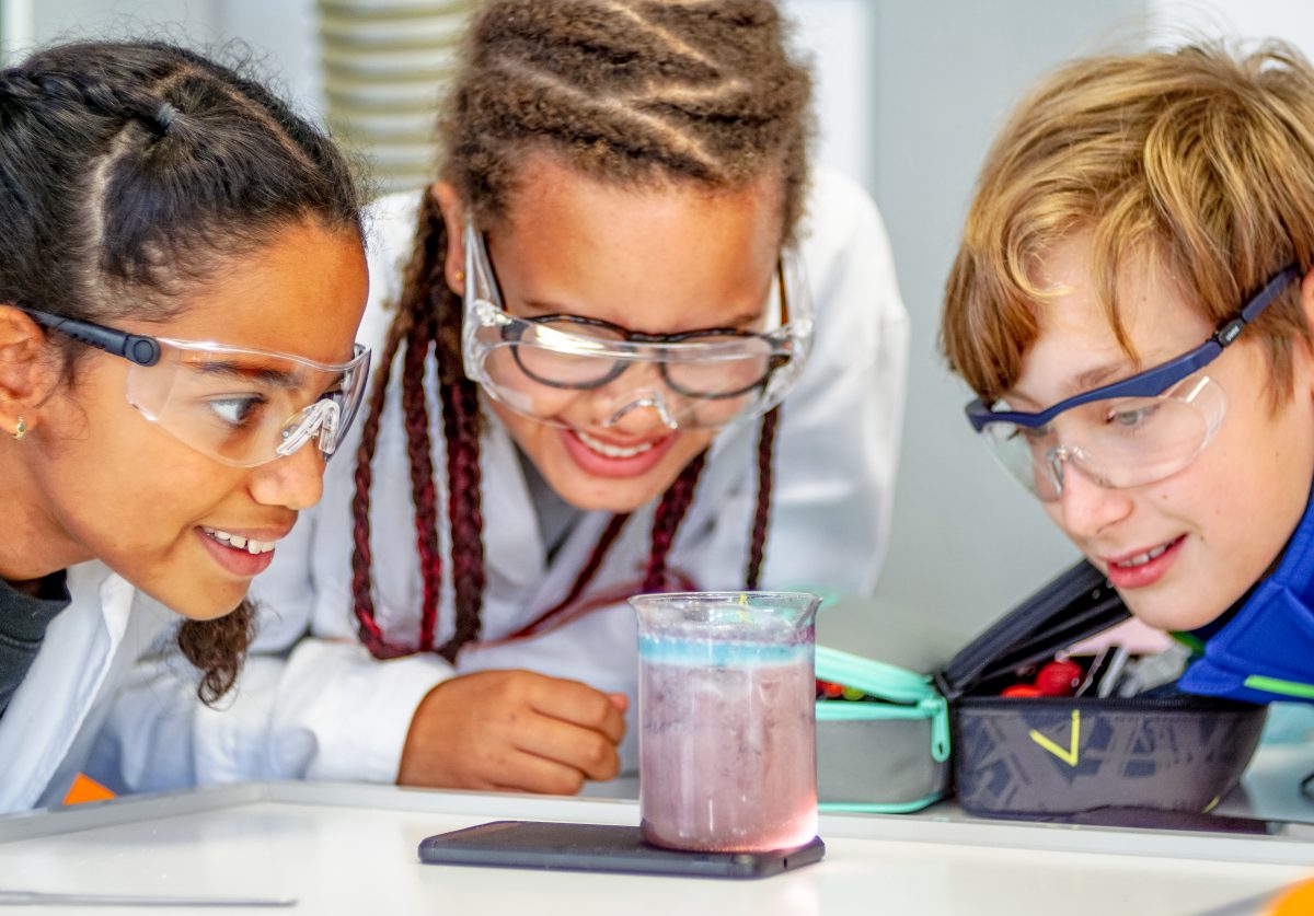 Drei Schüler begutachten ein Reagenzglas