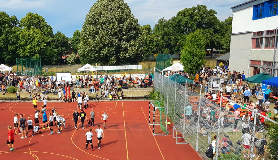 Hartplatz der Schule, auf dem ein buntes Treiben herrscht