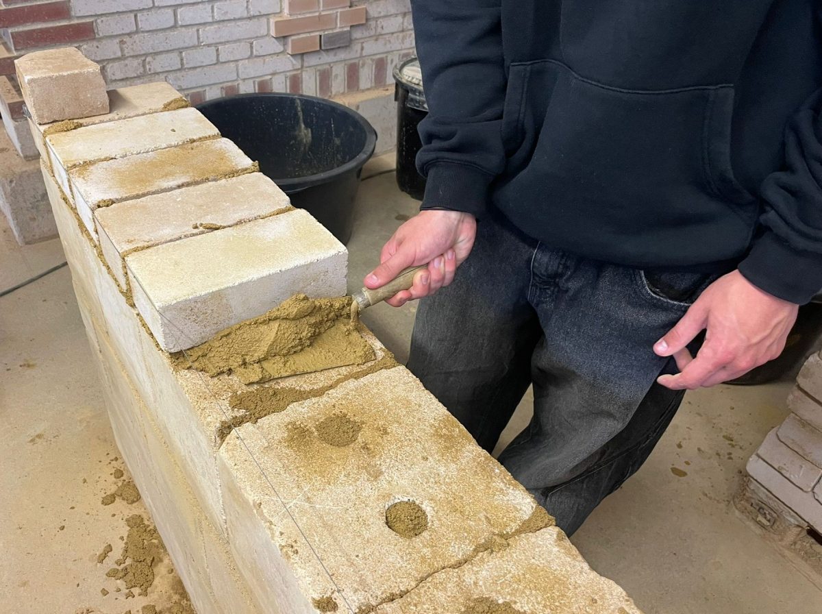 Ein Schüler baut eine Mauer mit Mörtel