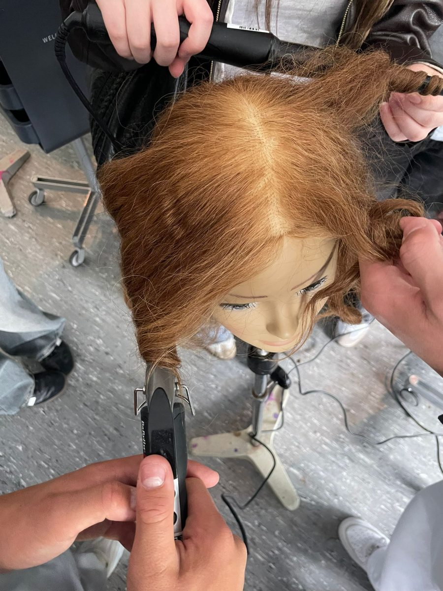 Schüler üben das Frisieren an einer Puppe
