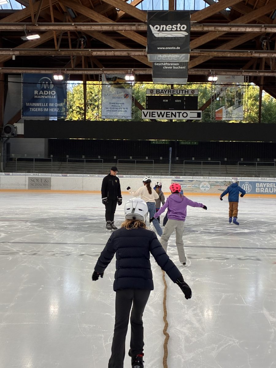 Mehrere Schüler laufen Schlittschuh im Eisstadion