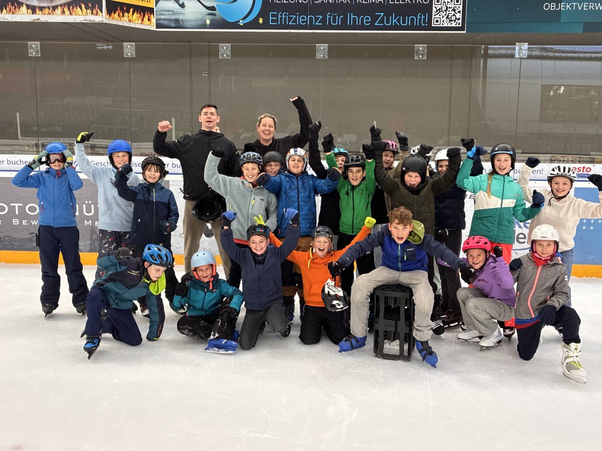Eine Schülergruppe steht in der Eislaufhalle auf dem Feld und jubelt
